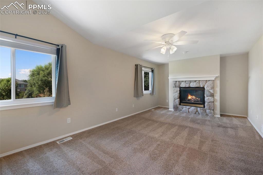 Image 18 of 37: Unfurnished living room with carpet flooring, a fireplace, and a ceiling fa
