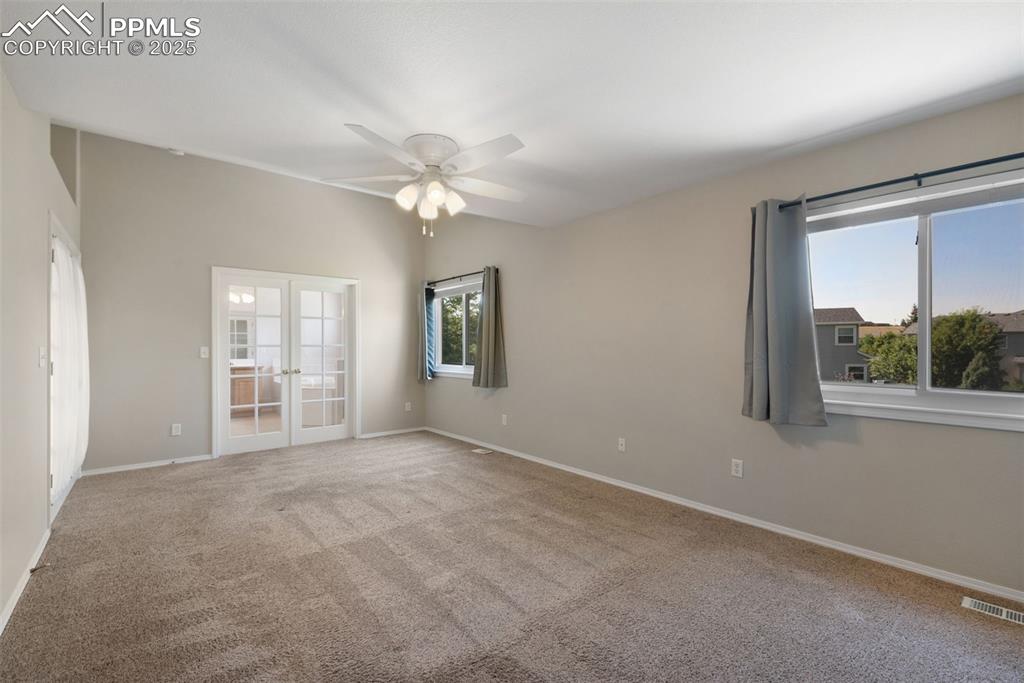 Image 21 of 37: Carpeted spare room with french doors and ceiling fan