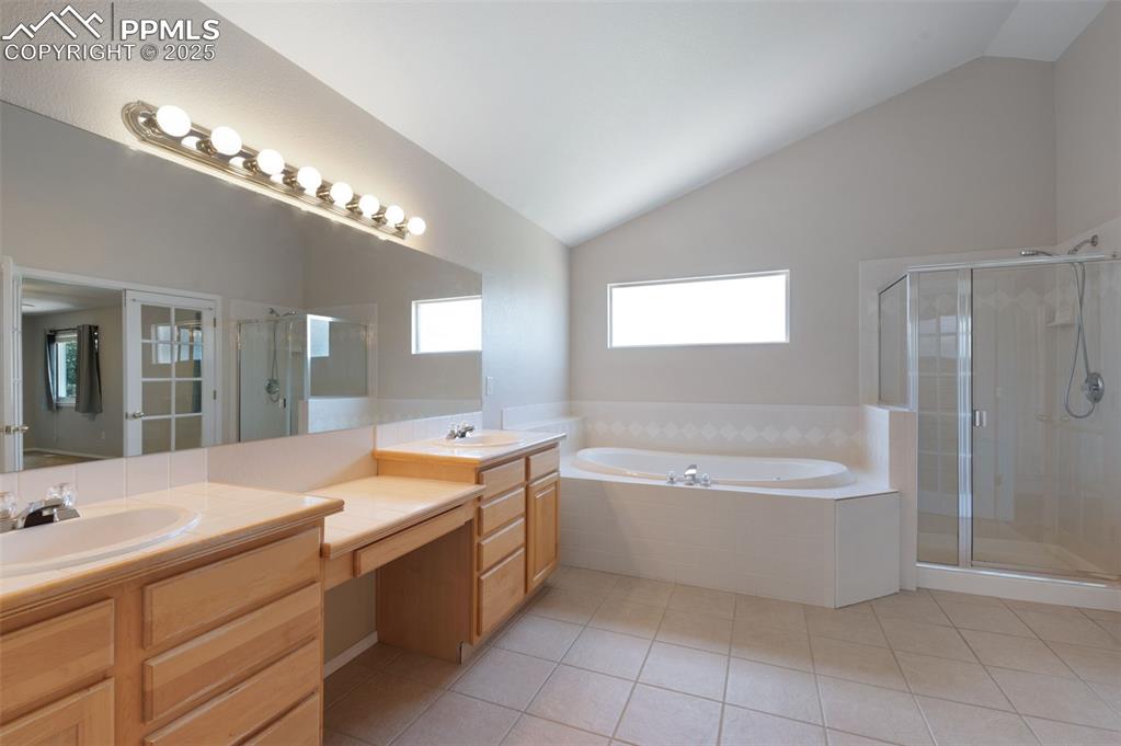 Image 22 of 37: Full bath with vaulted ceiling, light tile patterned floors, double vanity,