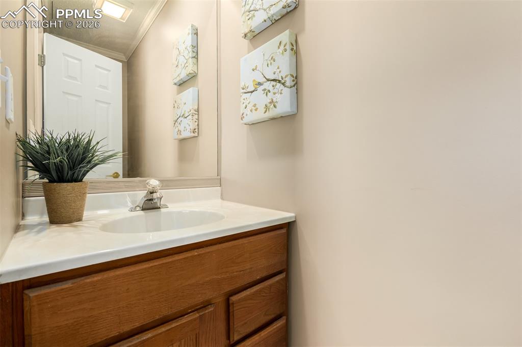Image 11 of 30: Half bathroom with vanity and crown molding