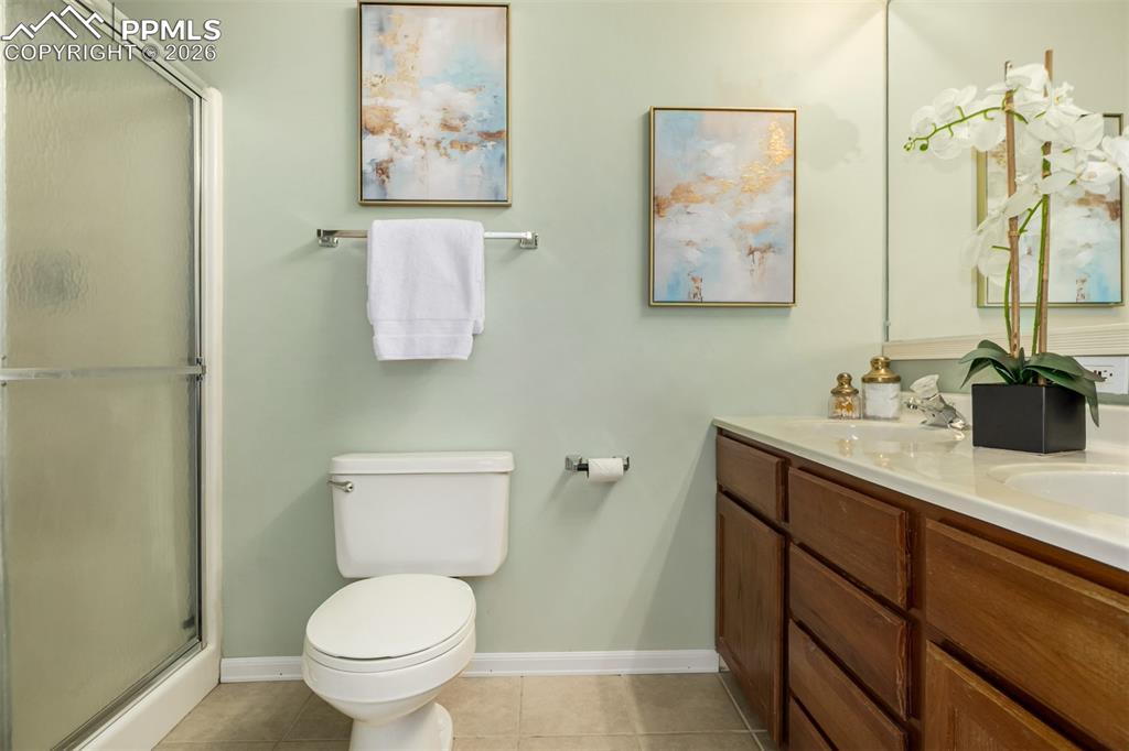 Image 15 of 30: Full bath featuring double vanity, a stall shower, and light tile floors