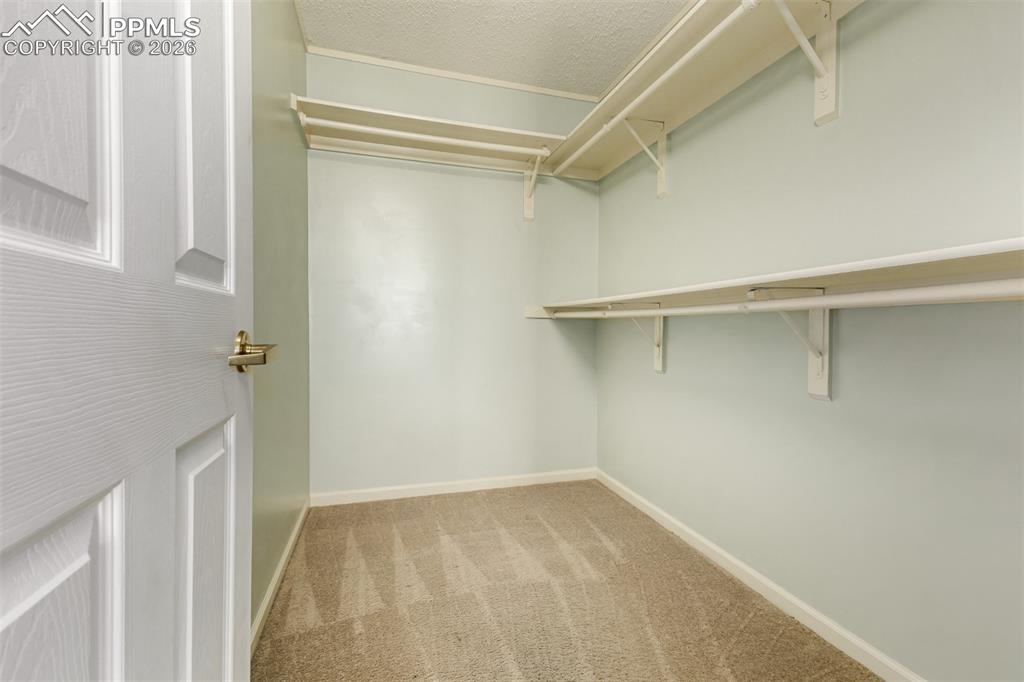 Image 17 of 30: Walk in closet with light colored carpet