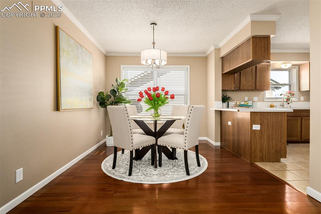 Image 7 of 30: Dining area with hardwood flooring, crown molding amd lots of natural light