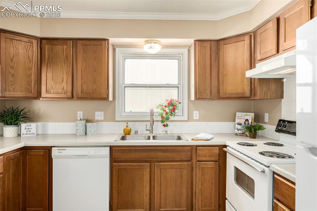 Image 8 of 30: Kitchen featuring white appliances, wood finish cabinetry, light countertop