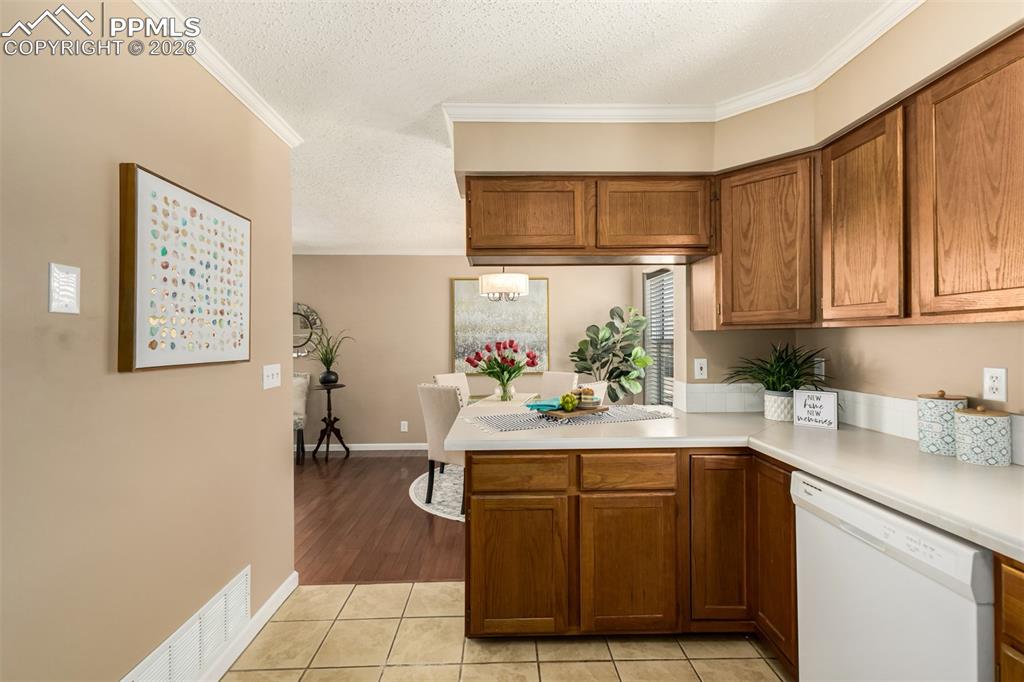 Image 9 of 30: Kitchen featuring wood finish cabinetry, light countertops, white dishwashe