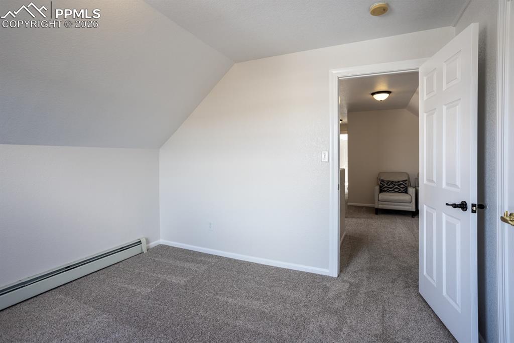 Image 25 of 50: Bonus room with a baseboard heating unit, carpet floors, vaulted ceiling, a