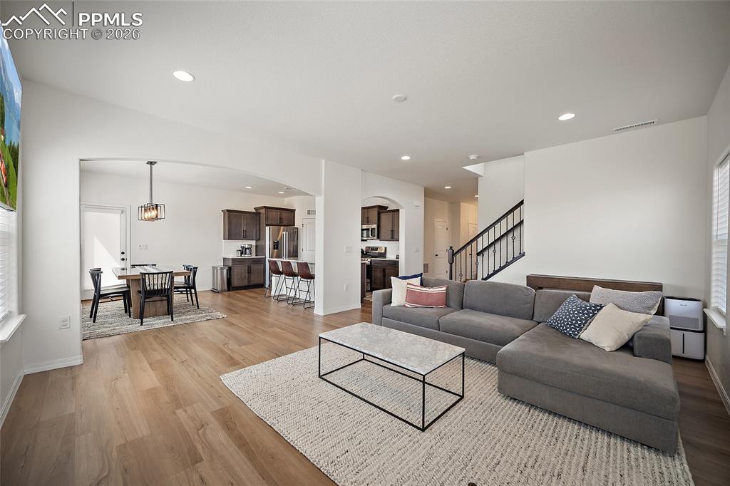 Image 11 of 45: Open-concept living space featuring wood-finish flooring, recessed lighting