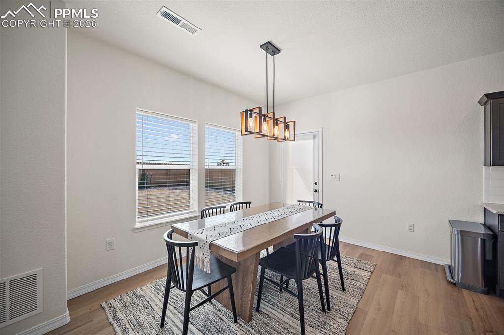 Image 12 of 45: Dining area featuring two windows with blinds, a modern linear chandelier, 