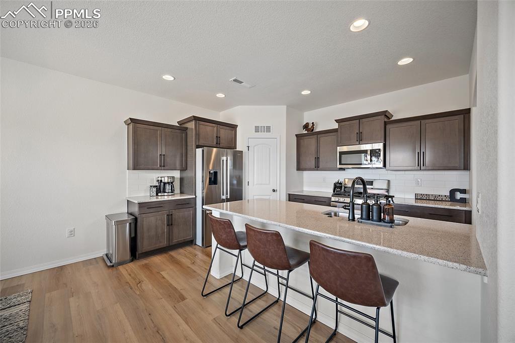 Image 13 of 45: Modern kitchen featuring wood-finish flooring, ample cabinetry, stainless s