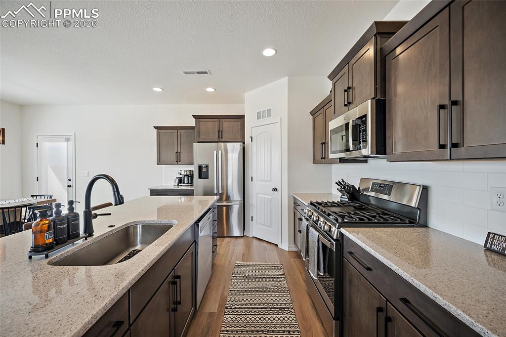 Image 14 of 45: Contemporary kitchen featuring dark wood-finish cabinetry, stainless steel 