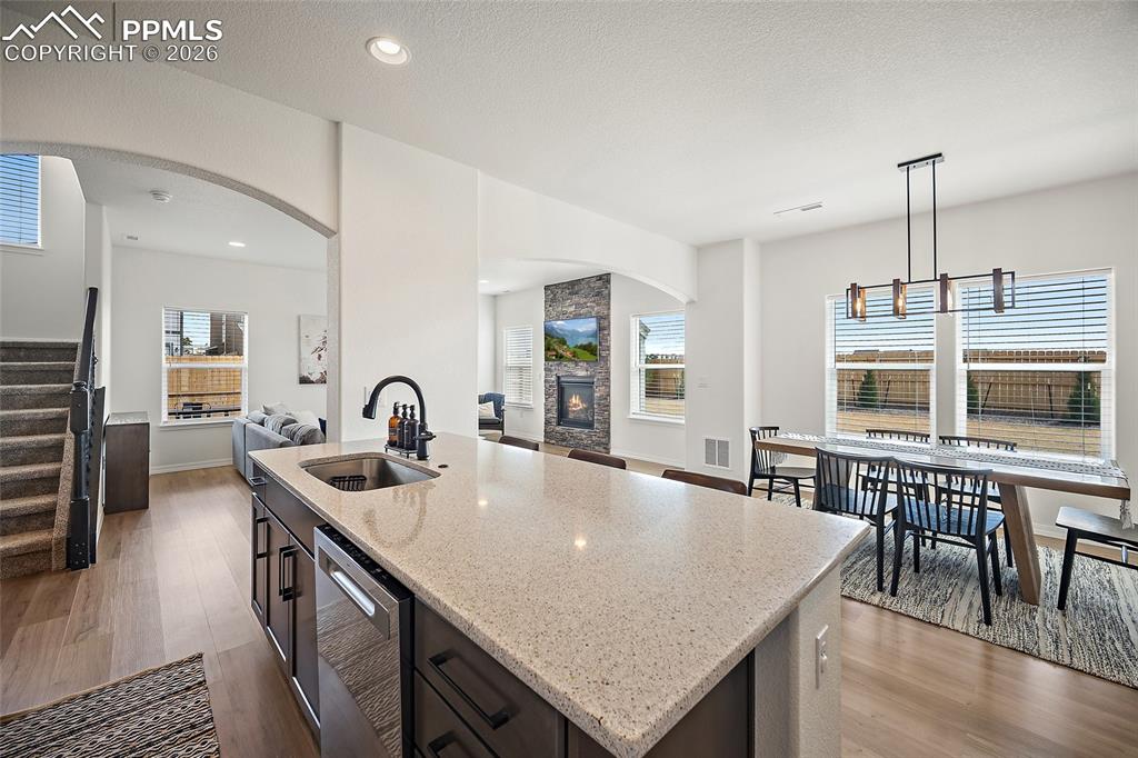 Image 15 of 45: Spacious kitchen island with a built-in sink, modern black faucet, and ligh
