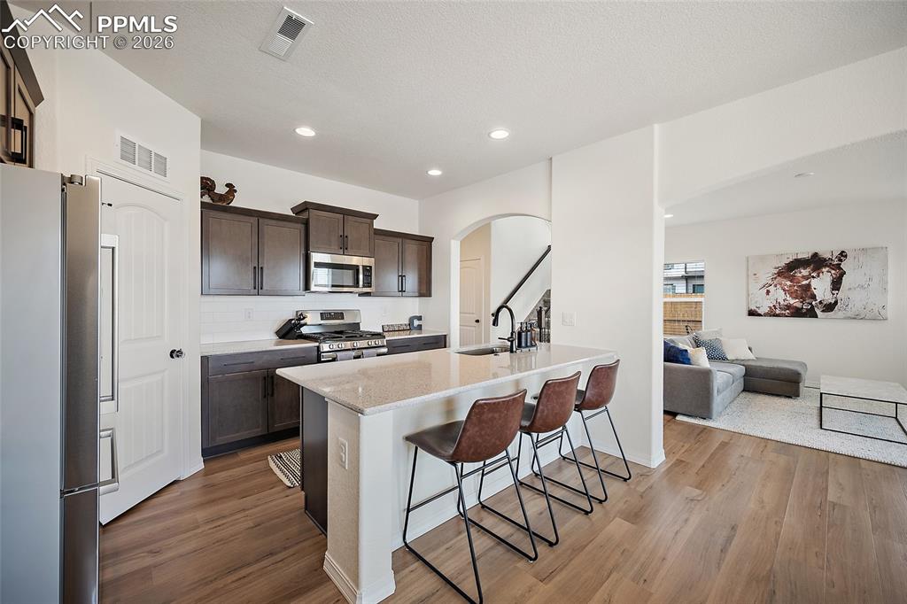 Image 16 of 45: Kitchen featuring dark wood cabinetry, stainless steel appliances, a tile b