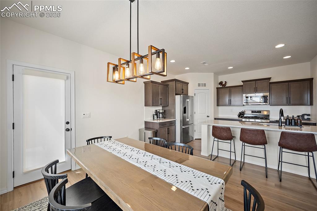 Image 18 of 45: Open-concept living space featuring a linear wood and metal chandelier, lig