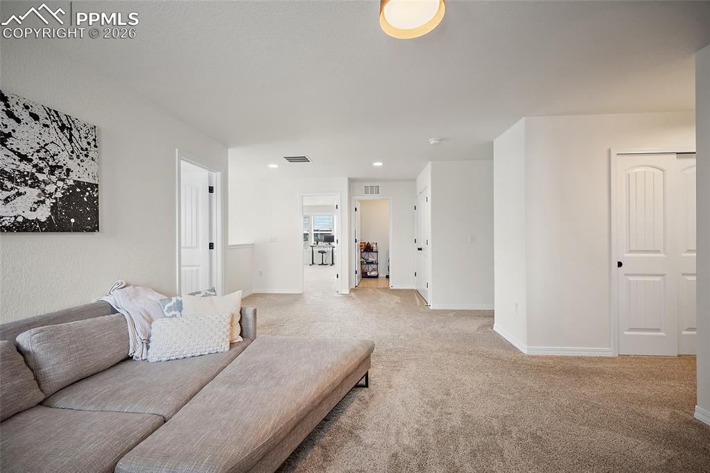Image 22 of 45: Expansive carpeted area with white walls, recessed lighting, and a modern f