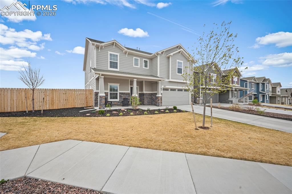 Image 3 of 45: Two-story residence featuring light gray siding with stone accents, a cover