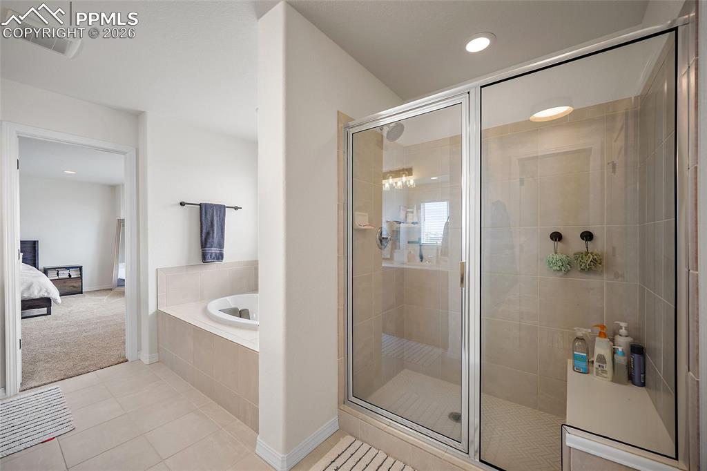 Image 31 of 45: Spacious bathroom featuring a built-in soaking tub, a separate glass-enclos