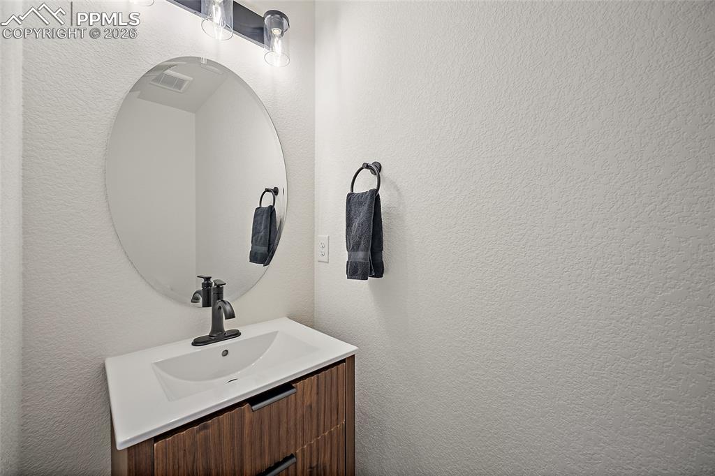 Image 38 of 45: Contemporary vanity featuring a wood-finish cabinet with textured doors, a 