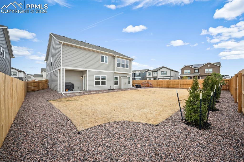 Image 40 of 45: Spacious backyard featuring a large central lawn area, gravel perimeter lan