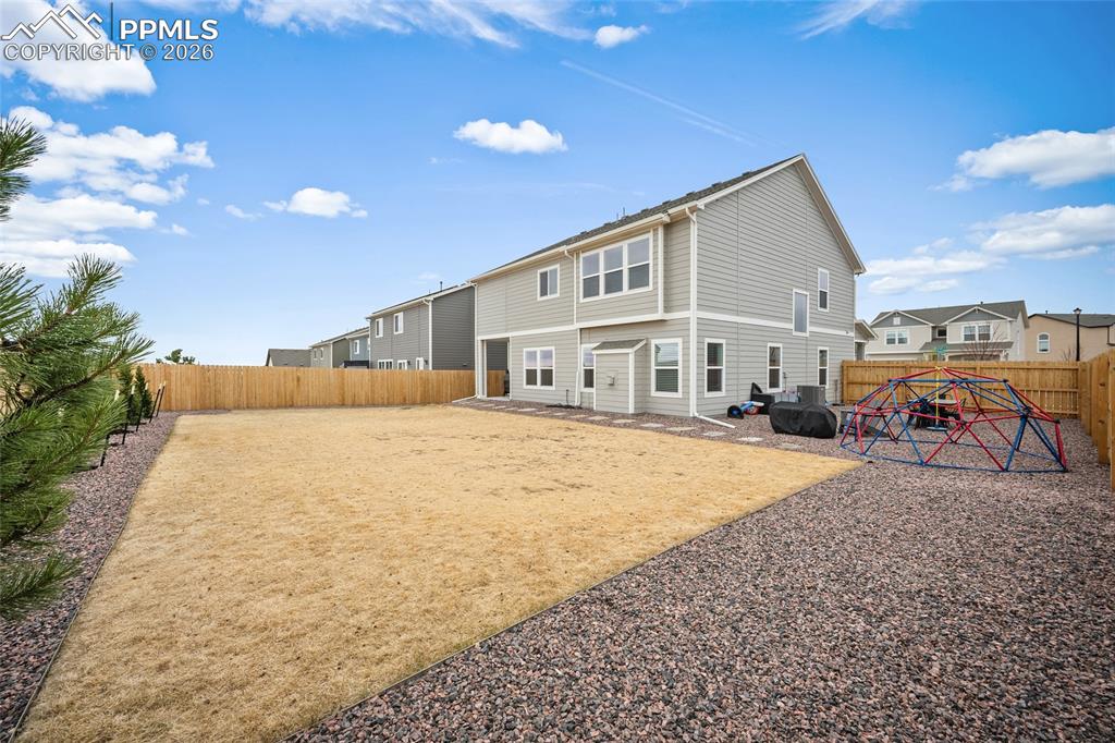Image 41 of 45: Spacious backyard featuring a full privacy fence, gravel border, and a larg