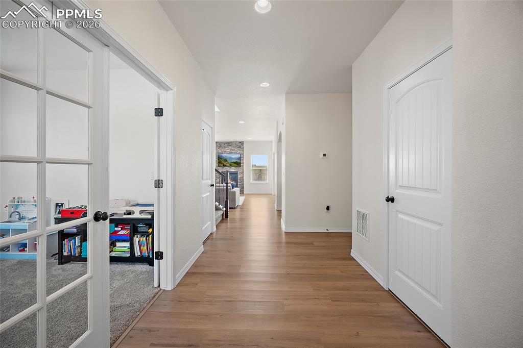 Image 5 of 45: Hallway with wood-finish flooring, recessed lighting, and a paneled interio