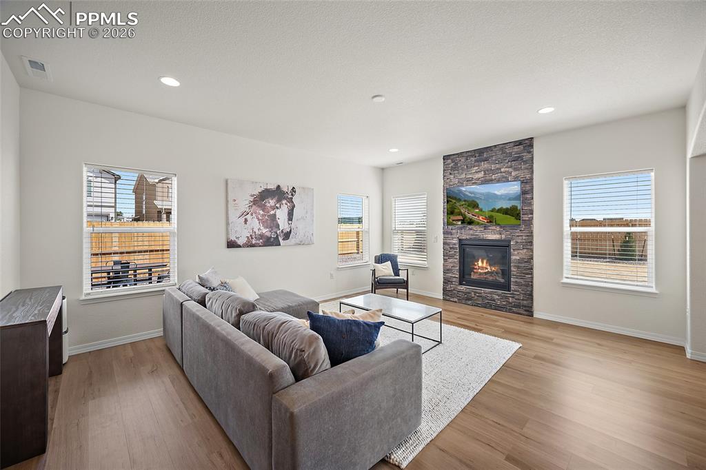 Image 8 of 45: Open-concept living space featuring a stacked stone fireplace with a mounte