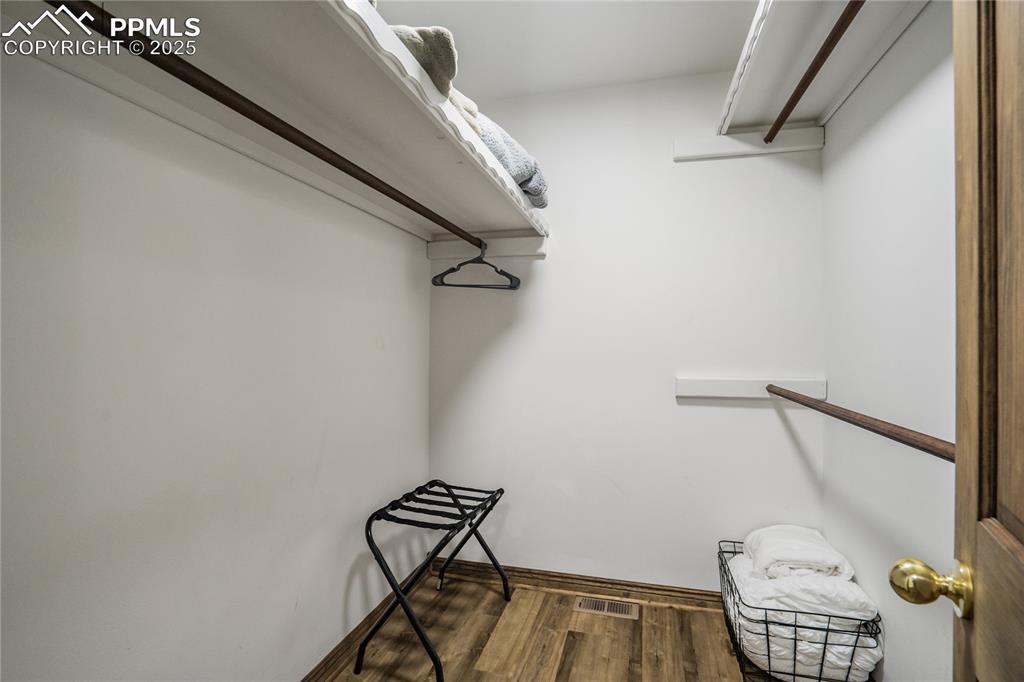 Image 14 of 50: Walk in closet in the primary bedroom with LVP flooring, shelves and hangin