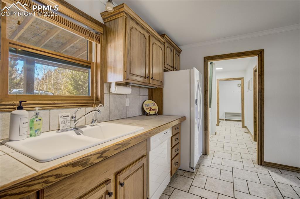 Image 5 of 50: Double sink, tile patterned floors, and brown cabinetry and views to the fr