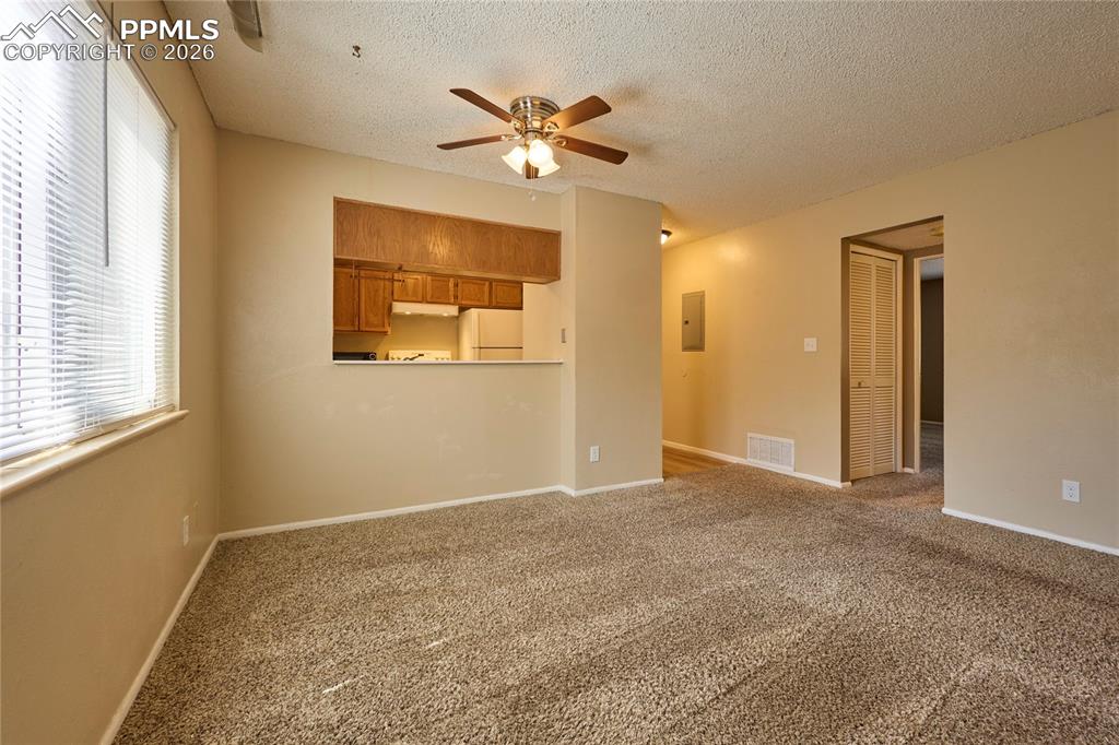 Image 12 of 28: Living/Dining room with carpet floors and a ceiling fan
