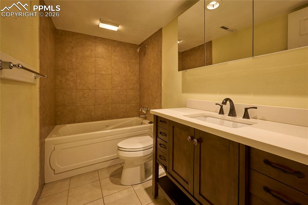Image 19 of 28: Full bath featuring tile floors, toilet, jetted bathtub / shower combinatio