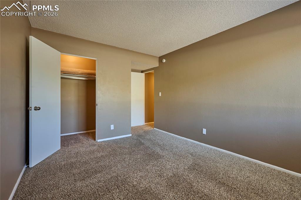 Image 21 of 28: Unfurnished bedroom with a textured ceiling, carpet floors, and closet
