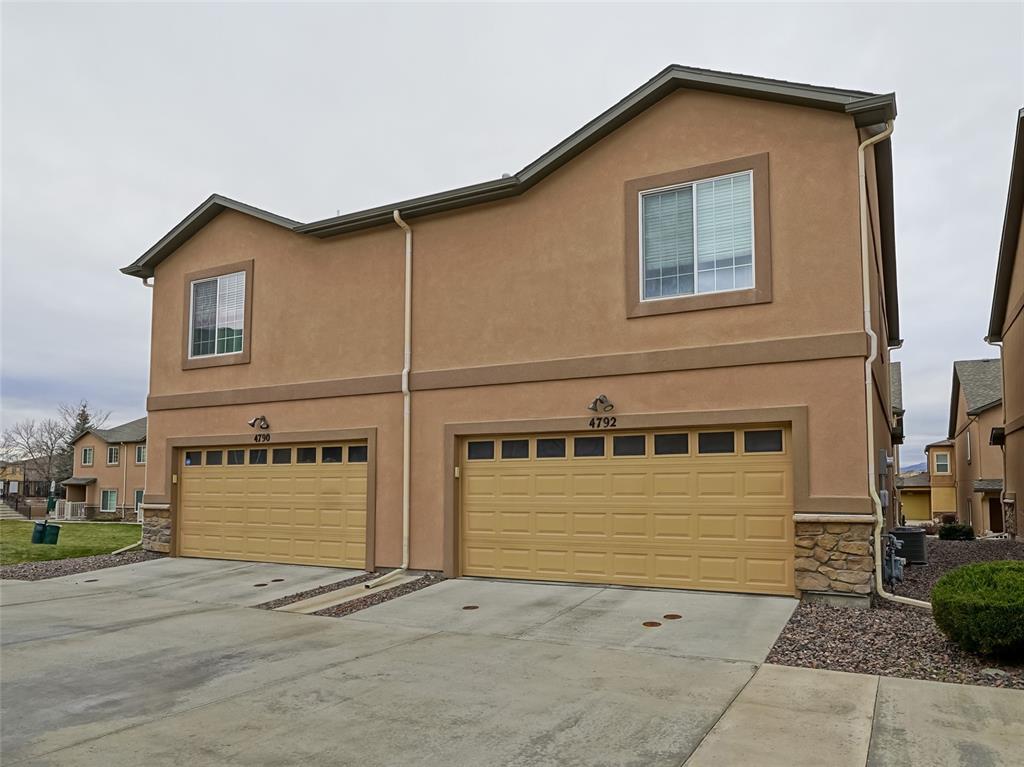 Caption: Traditional-style house featuring stone siding, stucco siding, a garage, and concrete driveway