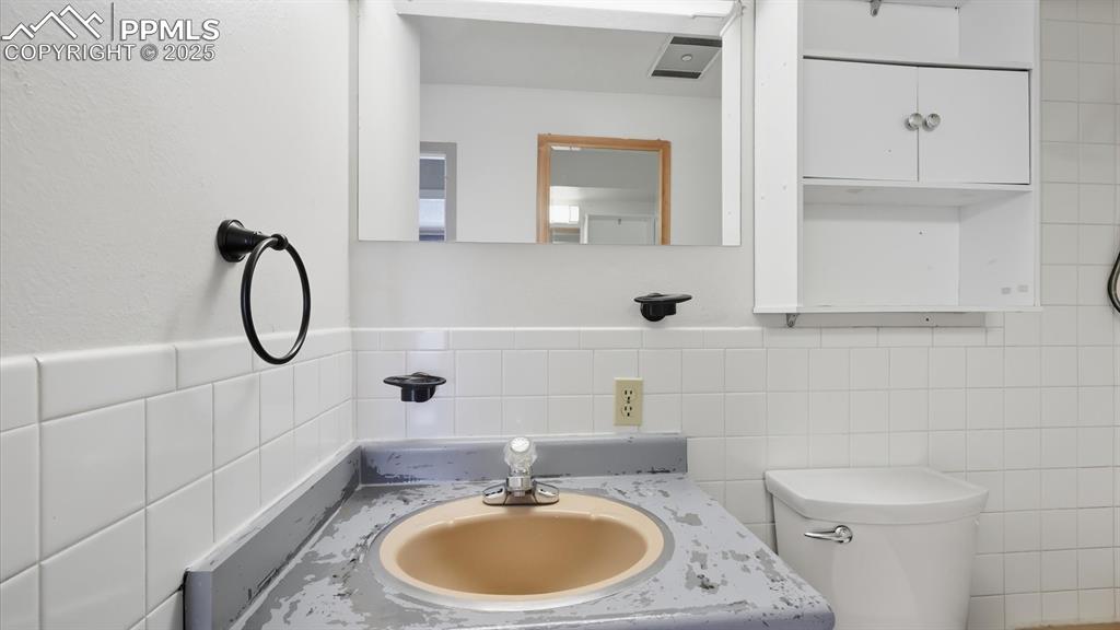 Image 20 of 31: Full Bathroom with vanity, mirror, and over the toilet cabinet.