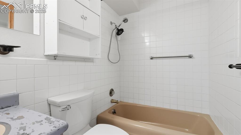 Image 21 of 31: Tub/shower combo with tiled surround to the ceiling.