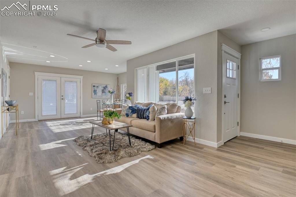 Image 17 of 48: Living area with french doors, light wood finished floors, recessed lightin
