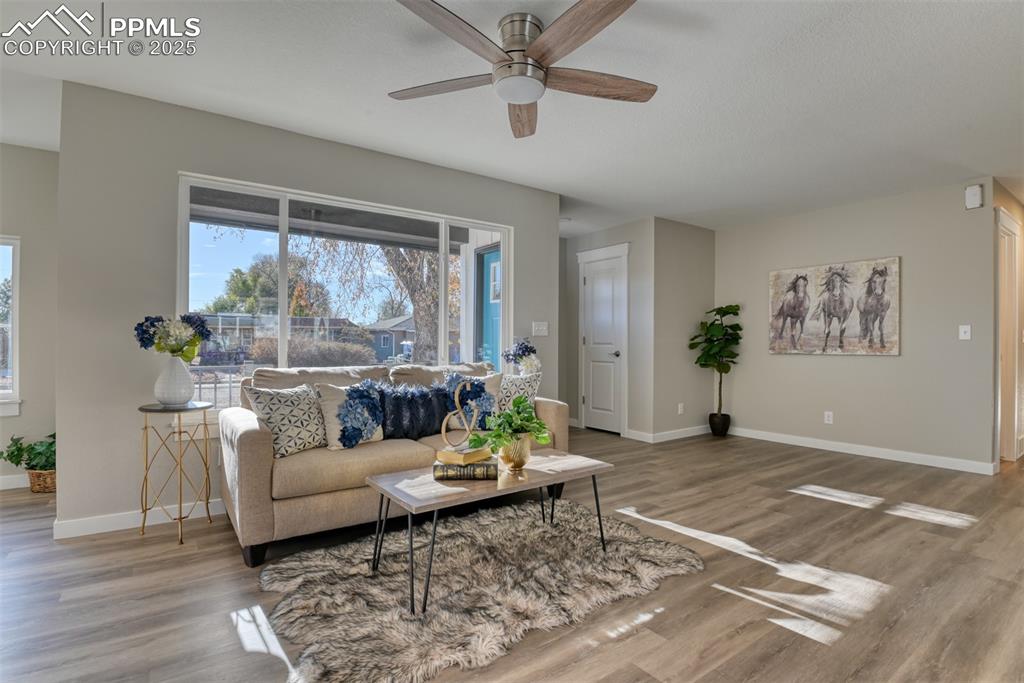 Image 18 of 48: Living room with light wood-style floors and ceiling fan