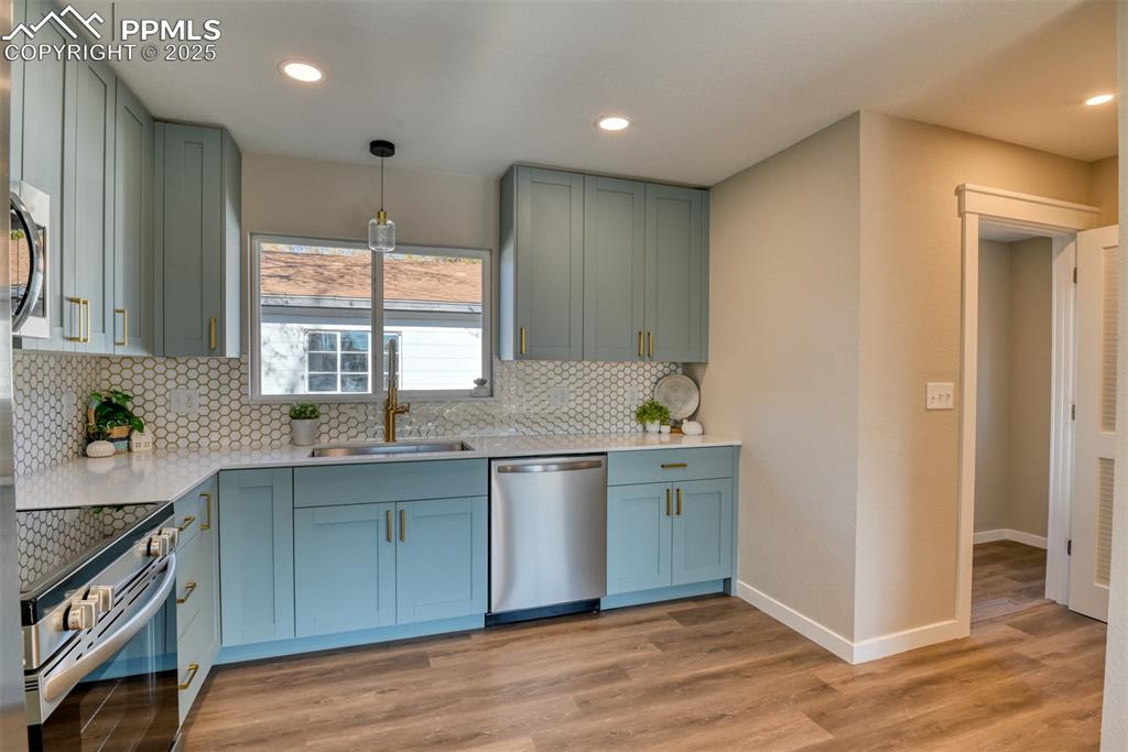 Image 27 of 48: Kitchen featuring appliances with stainless steel finishes, light stone cou