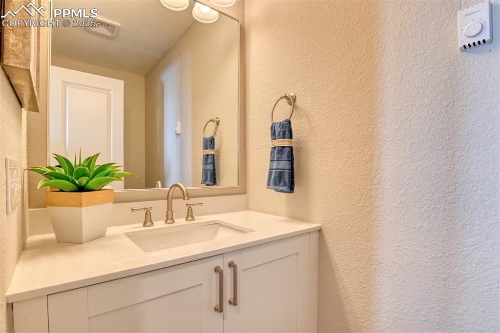 Image 31 of 48: Bathroom with a textured wall and vanity