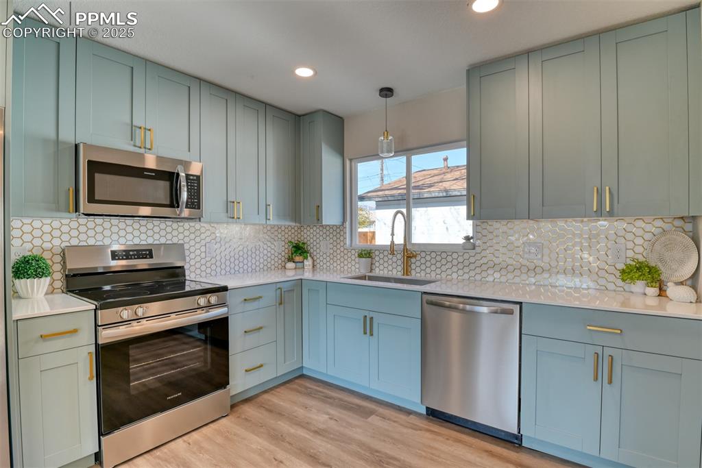 Image 32 of 48: Kitchen featuring appliances with stainless steel finishes, hanging light f