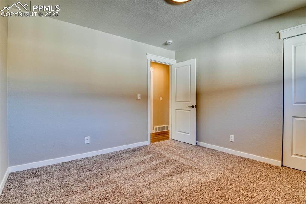 Image 46 of 48: Empty room with light carpet and a textured ceiling
