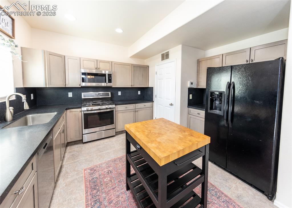 Image 12 of 50: Kitchen includes tile flooring, large stainless sink w/disposal, built-in B