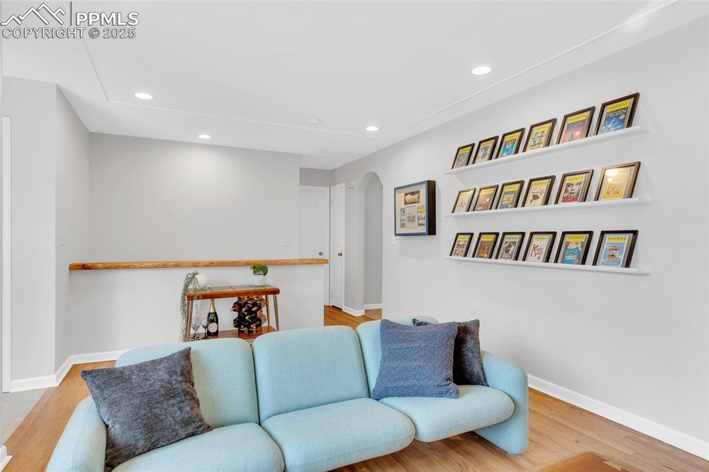 Image 11 of 50: Living area featuring arched walkways, wood finished floors, and recessed l