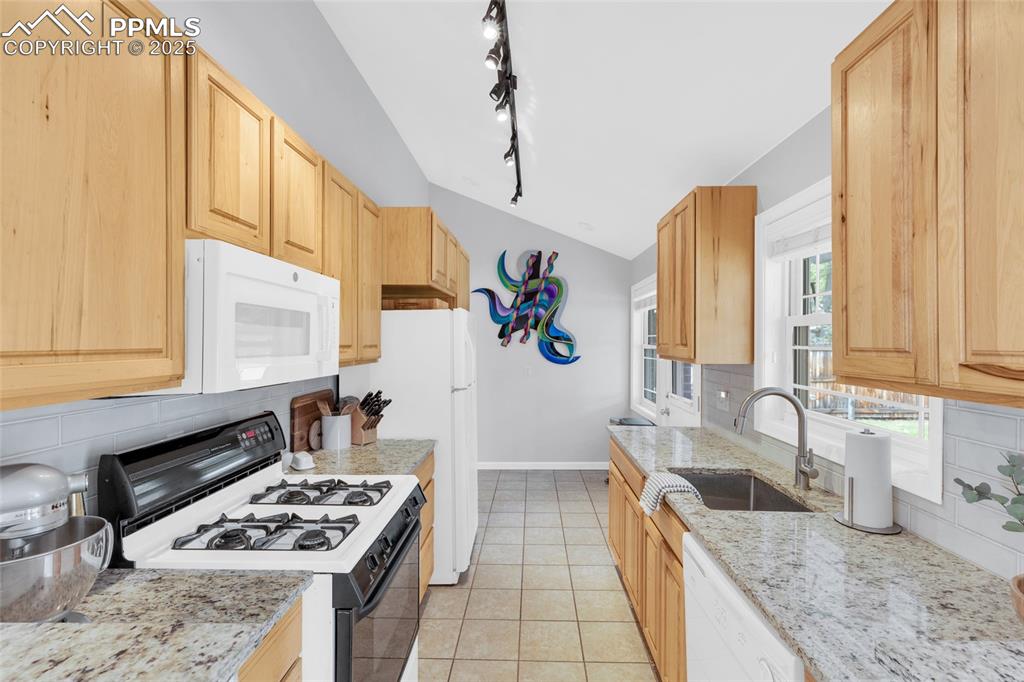 Image 15 of 50: Kitchen featuring tasteful backsplash, white appliances, light tile pattern