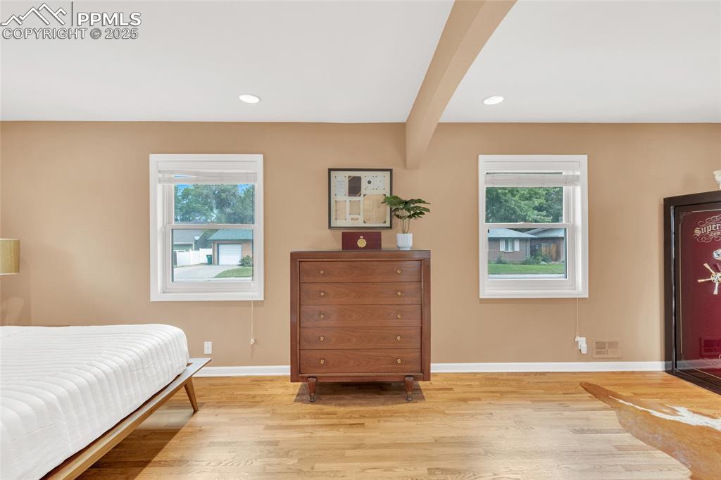 Image 20 of 50: Bedroom with beam ceiling, light wood-style floors, and recessed lighting