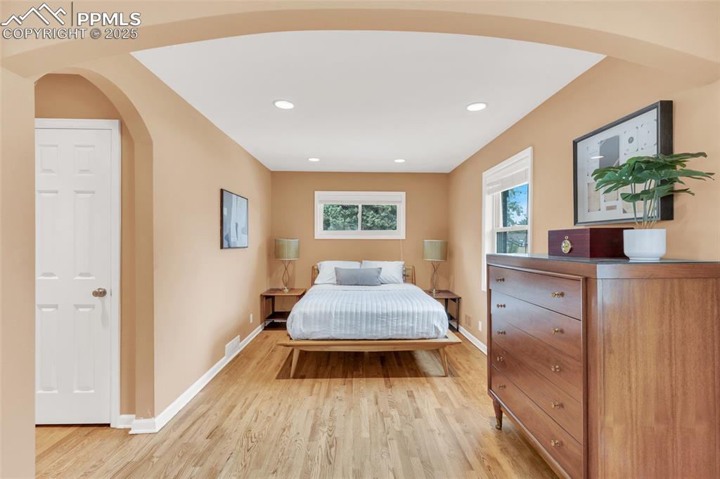 Image 21 of 50: Bedroom with arched walkways, light wood-style flooring, and recessed light