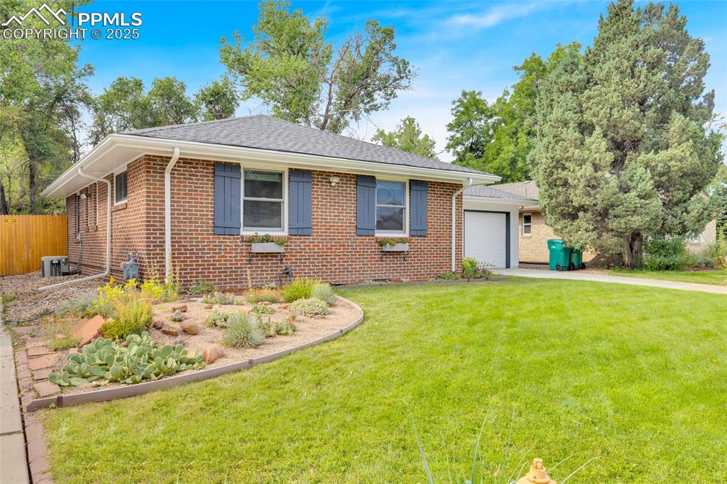 Image 3 of 50: View of front facade featuring brick siding, an attached garage, concrete d