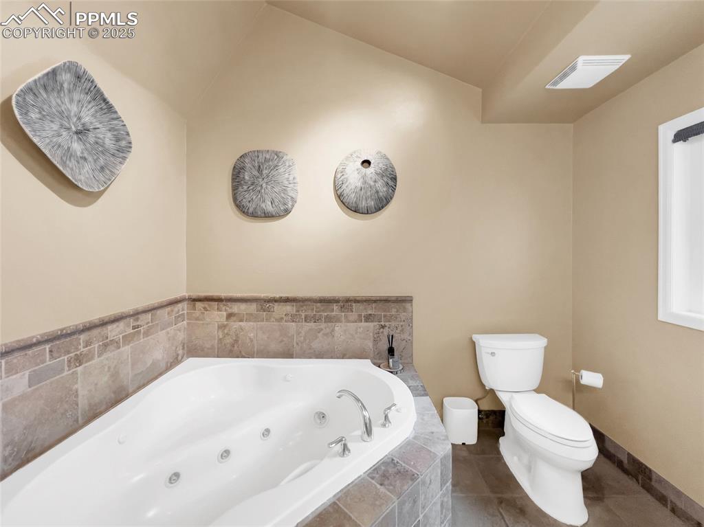 Image 36 of 50: Full bath with a jetted tub and tile patterned floors