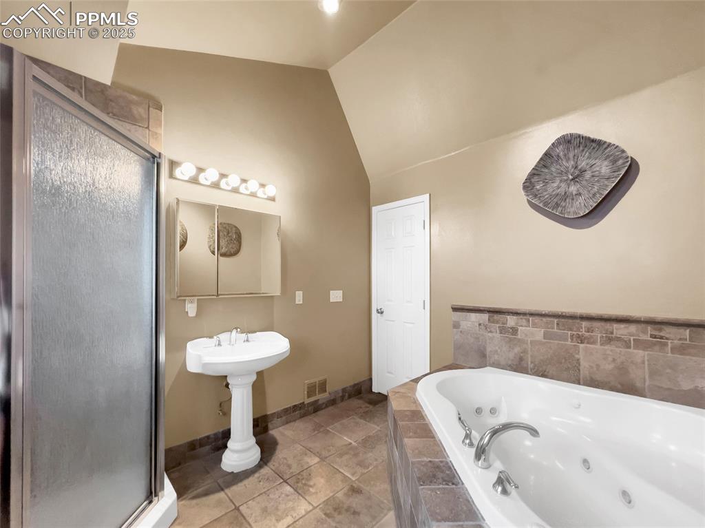 Image 37 of 50: Full bathroom with lofted ceiling, a stall shower, and a whirlpool tub