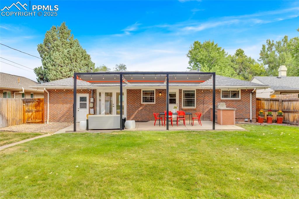 Image 44 of 50: Back of property featuring a fenced backyard, a patio, and brick siding