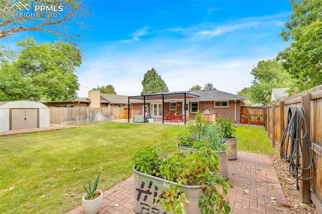 Image 45 of 50: Fenced backyard featuring a patio area, a storage shed, and a pergola