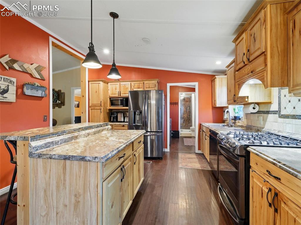 Image 10 of 45: Kitchen with stainless steel fridge, range with gas cooktop, custom tile ba